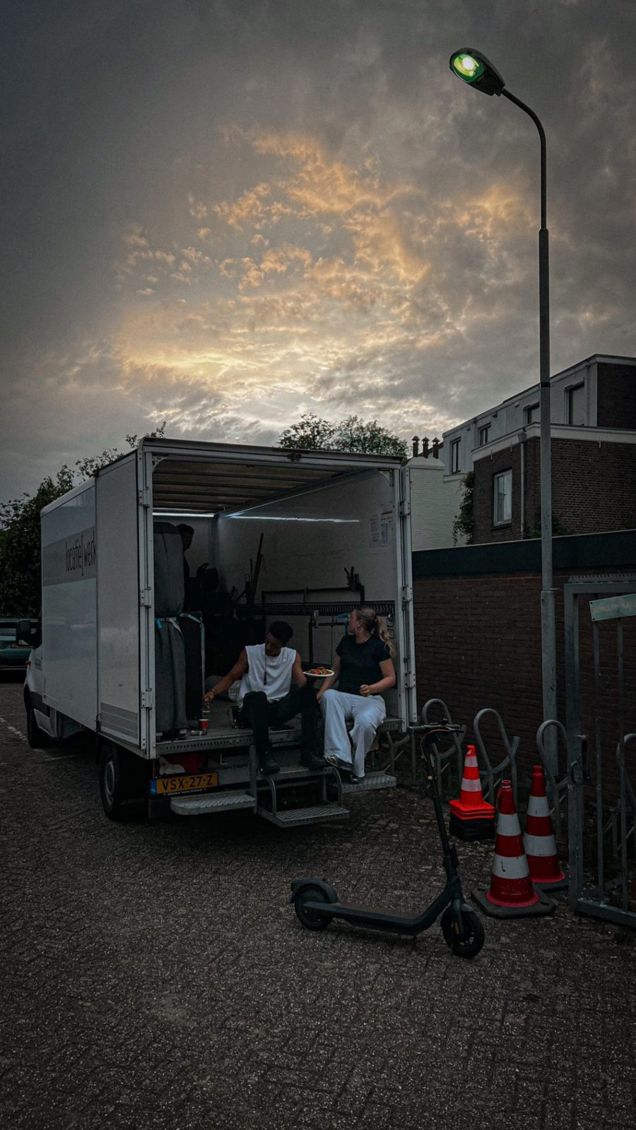 Crew eating in the open box truck, with cones beside it
