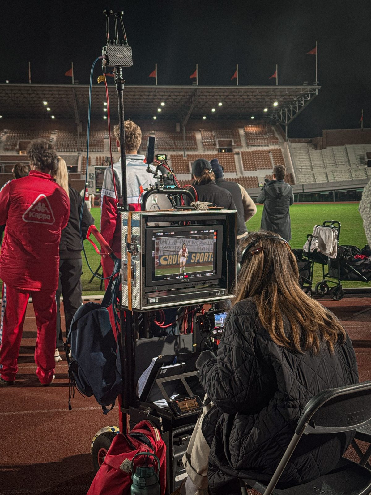 Monitors and crew at a night shoot in a stadium