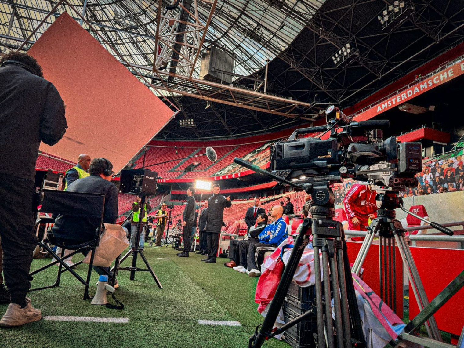 Cameras and crew along the pitch in a stadium