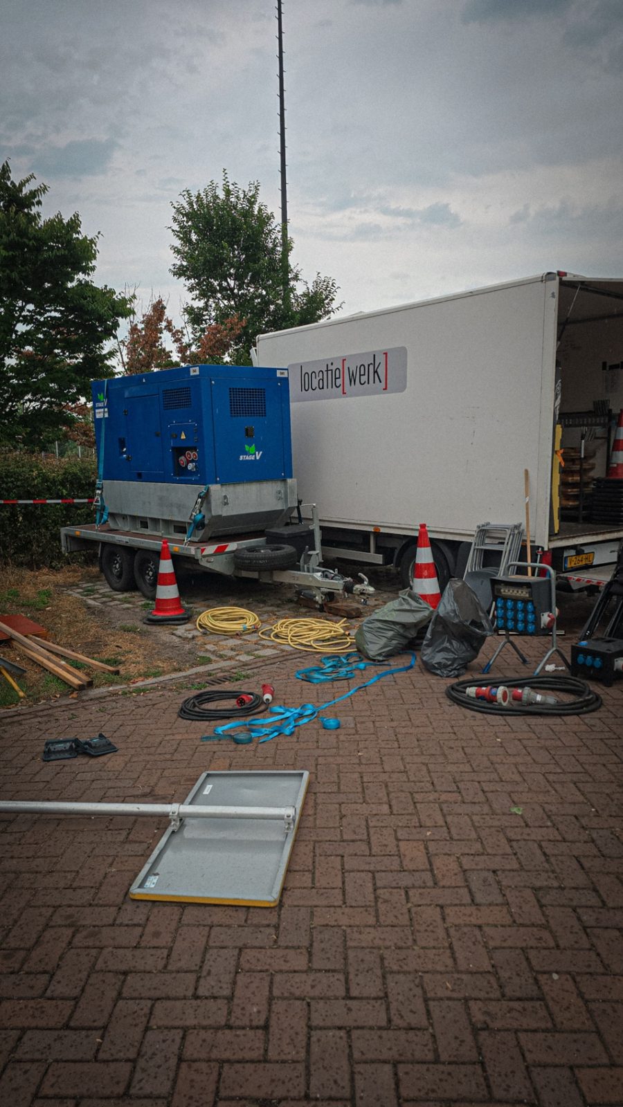 Aggregaat, kabels en een bakwagen bij de set