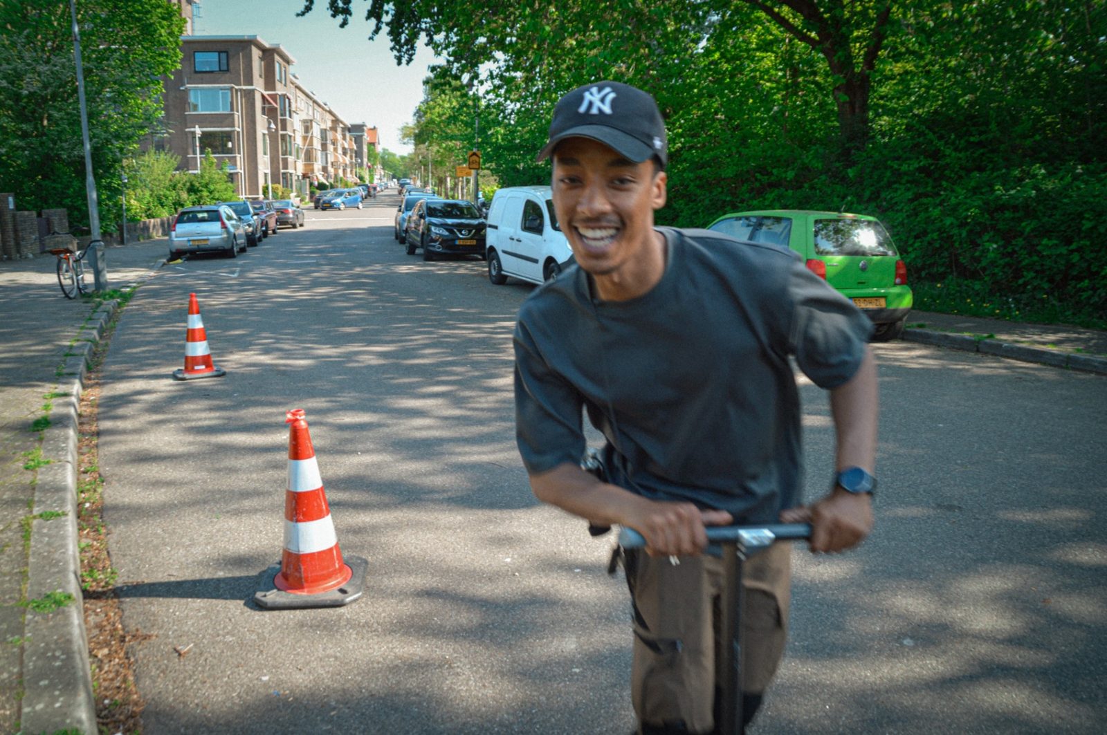 Issam laughing on a scooter past the cones in the street
