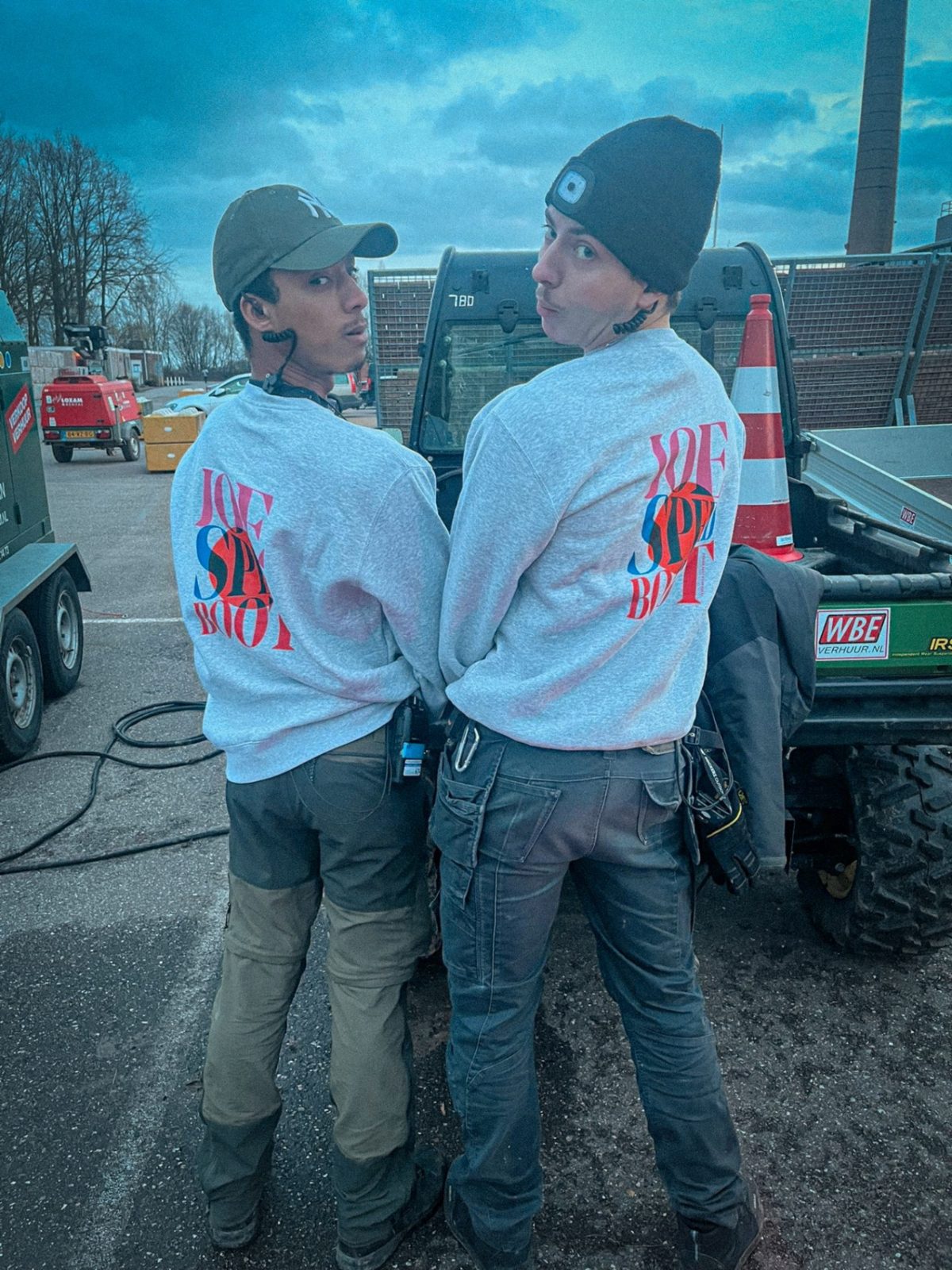 Two crew members seen from behind, next to a golf cart