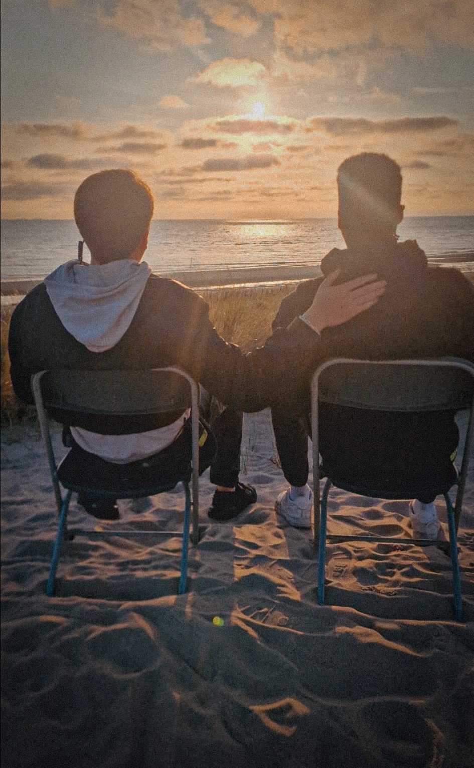 Two crew members watch the sunset on the beach after a shoot day