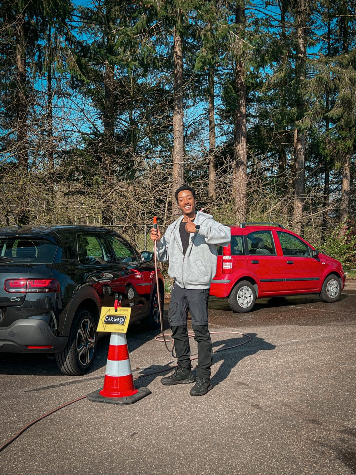 Issam smiling next to a cone with a cable sign in the car park